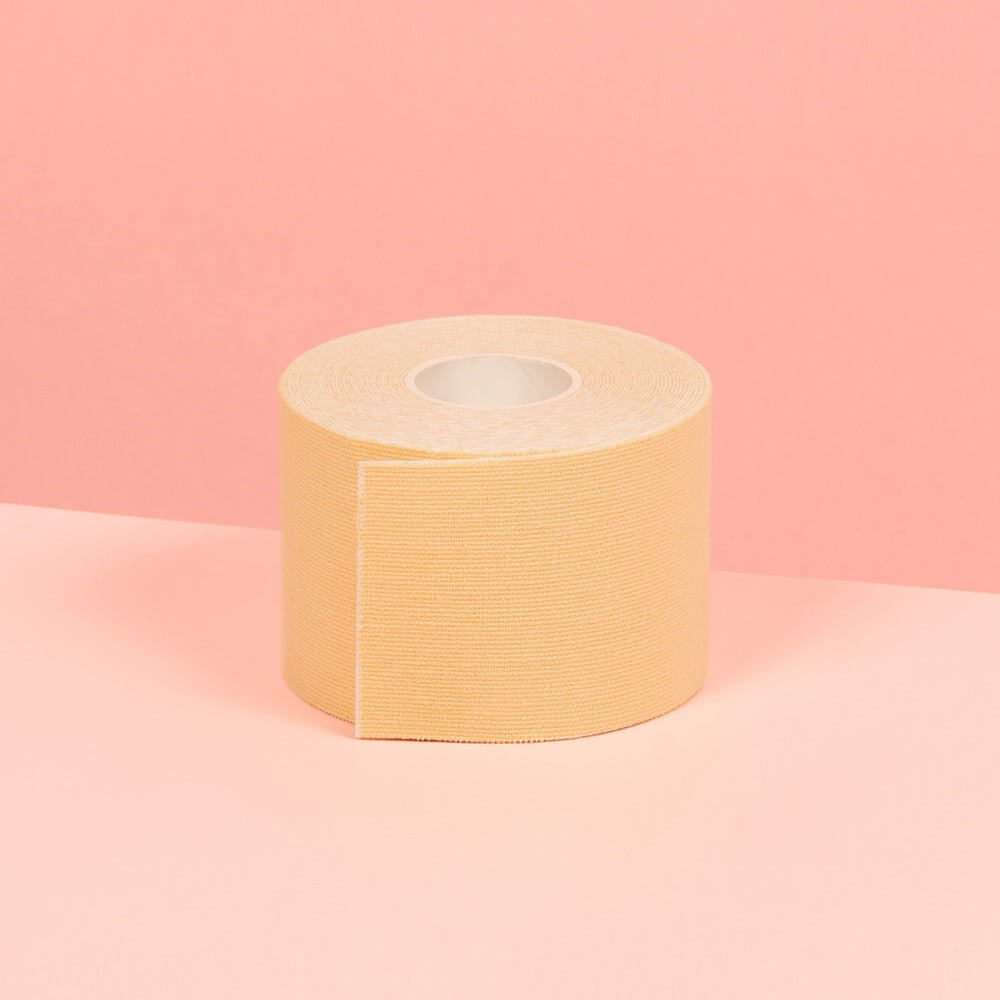 5 cm beige double sided boob tape is showcased on a pink table.